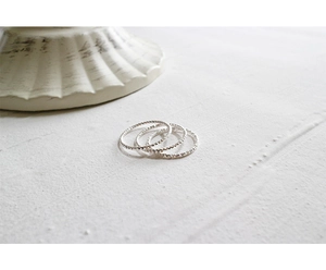 Macro detail of three slim 925 silver rings with twisted texture for stacking style