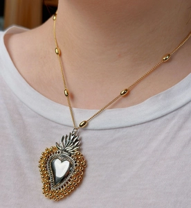 Close-up of 18k gold and silver heart pendant with beaded trim on a chain necklace