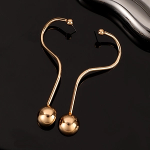 Gros plan de boucles d'oreilles dorées en S avec billes polies sur fond noir brillant