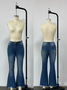 Detail of high waisted flared blue jeans featuring frayed hems and washed denim texture