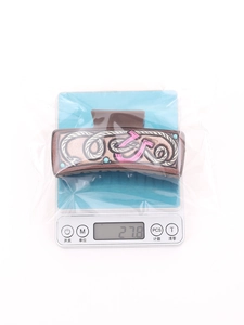 Detail view of a 27.8g western style brown hair claw clip with pink pattern on scale