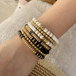 Close-up of bohemian beaded bracelet set in gold, black and white layered on wrist