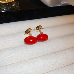 Detailed macro view of retro red oval earrings on a premium beige velvet display