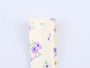 Détail de tissu satiné à fleurs violettes avec imprimé rose sur fond blanc crème