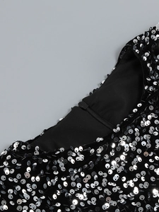 Détail de paillettes argentées sur robe noire avec fermeture éclair invisible et doublure