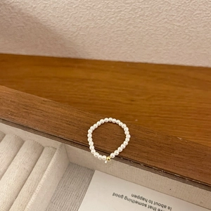 Close-up of mini freshwater pearl elastic ring with a single gold bead on a wooden tray