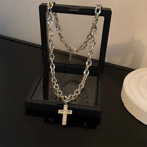 Titanium steel cross necklace in silver and gold tone on a black jewelry display box