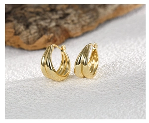 Macro shot of double-layered gold hoop earrings with smooth metallic striped texture