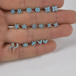 Turquoise nose stud set with snake and flower designs shown on finger for scale