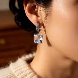 Elegant C-shaped silver earrings with vintage square glass crystals worn by a model