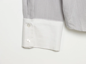 Detail of grey striped shirt sleeve with white double-button cuff and precise stitching