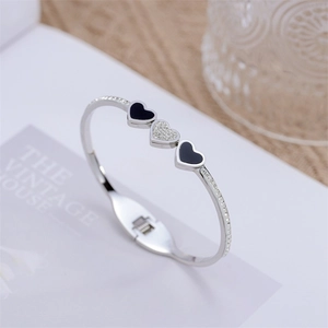 Dettaglio di bracciale rigido a cuore argento con smalto nero e cristalli su base bianca