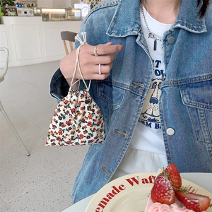 Detailed view of floral corduroy drawstring bag held in a cozy cafe setting