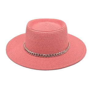 Detail of salmon pink boater hat featuring fine woven texture and silver chain trim