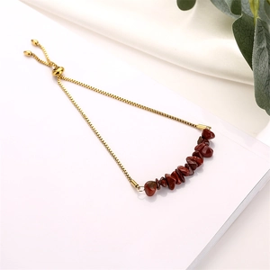Close-up of golden adjustable chain bracelet featuring red natural crushed stone beads