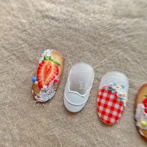 Close-up of strawberry and ballet-style embossed 3D nail art stickers on linen fabric