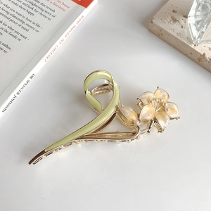 Detailed close-up of a lily flower hair claw clip with pearls and yellow enamel finish