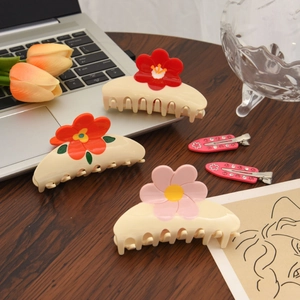 Vue à plat de pinces à cheveux à fleurs en acétate colorées sur un bureau en bois