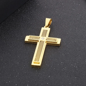 Gros plan sur un pendentif croix dorée avec texture maillée et diamant sur fond noir