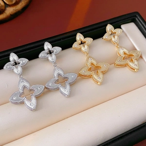 Detailed view of gold and silver hollow flower earrings with zircons in a box