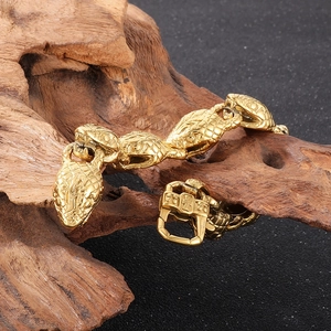 Detail of 18k gold plated stainless steel snake head bracelet on wooden decor