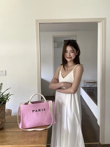 Detailed view of pink woven straw tote bag with Paris embroidery and long shoulder straps