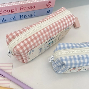 Close-up of pink and blue plaid canvas pencil cases with zippers and decorative labels