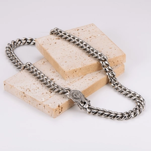 Silver Cuban link chain necklace featuring a lion head relief buckle on beige stone