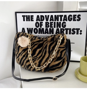 Detailed close-up of plush zebra print tote bag with gold chain and faux fur pom pom