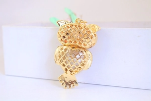 Macro view of golden alloy owl pendant featuring intricate hollow filigree on the back