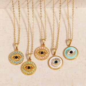 Detail showing five colorful evil eye pendants in gold necklaces on beige fabric background