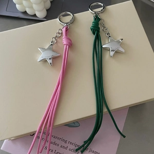 Detailed view of pink and dark green woven star pendants on a beige gift box and book