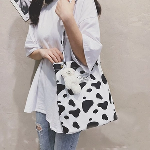 Detail of canvas tote bag with cow print pattern and cute white plush bear charm