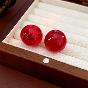 Detailed macro view of red resin stud earrings with gold foil and ice-cracked texture