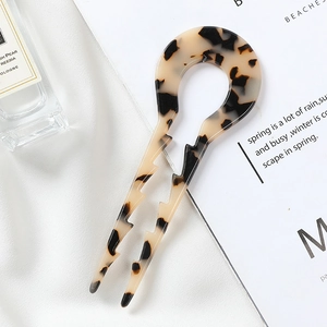 Close-up of tortoise shell U-shaped hair pin with anti-slip grooves on silk fabric
