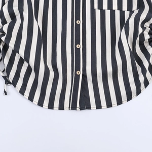 Detail of black and white striped shirt featuring curved hem and light wooden buttons