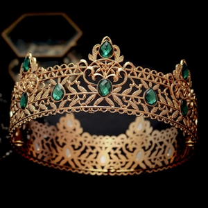 Close-up of vintage golden baroque crown with emerald water-drop gemstones and filigree