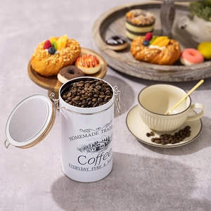 White airtight coffee tin with wooden lid and metal clasp filled with roasted beans