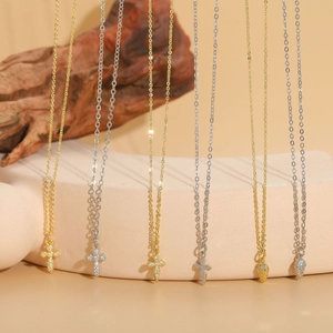 Close-up of gold and silver cross pendants with zircon stones on thin chain necklaces