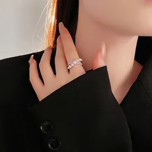 Crossed pearl ring with zircon accents on finger, elegant minimalist jewelry for women