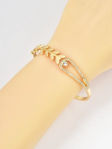 Close-up of golden wheat leaf bracelet featuring crystal-encrusted teardrop detail