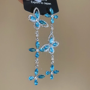 Macro shot of silver butterfly tassel earrings with blue gemstones and sparkling diamonds