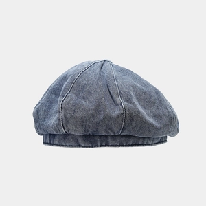Close-up of blue denim beret fabric texture and stitching details with top button