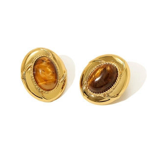 Detail view of vintage oval clip-on earrings with gold texture and amber resin stone