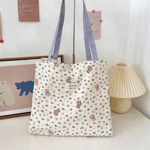 Detailed view of quilted tote bag featuring cartoon bear patterns and purple straps