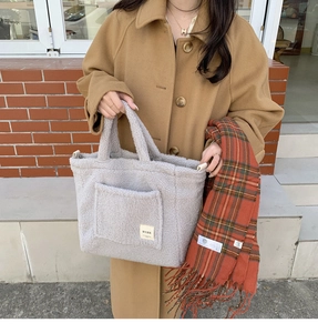 Detail of grey fleece tote bag featuring a stitched square label and soft lamb-like texture