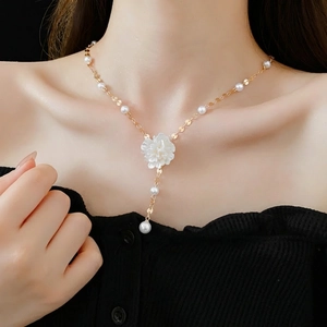 French style Y-shaped gold necklace with white flower pendant and pearls on a model