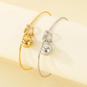 Minimalist knotted cuff bracelet with steel beads in gold and silver finish on display