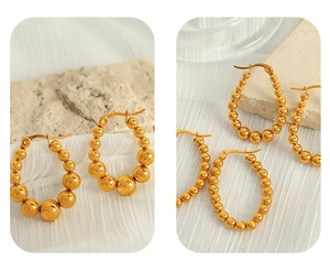 Detailed view of elegant gold beaded hoop earrings on natural stone and white fabric