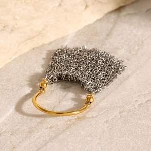 Two-tone gold and silver stainless steel chain tassel ring on a minimalist stone background
